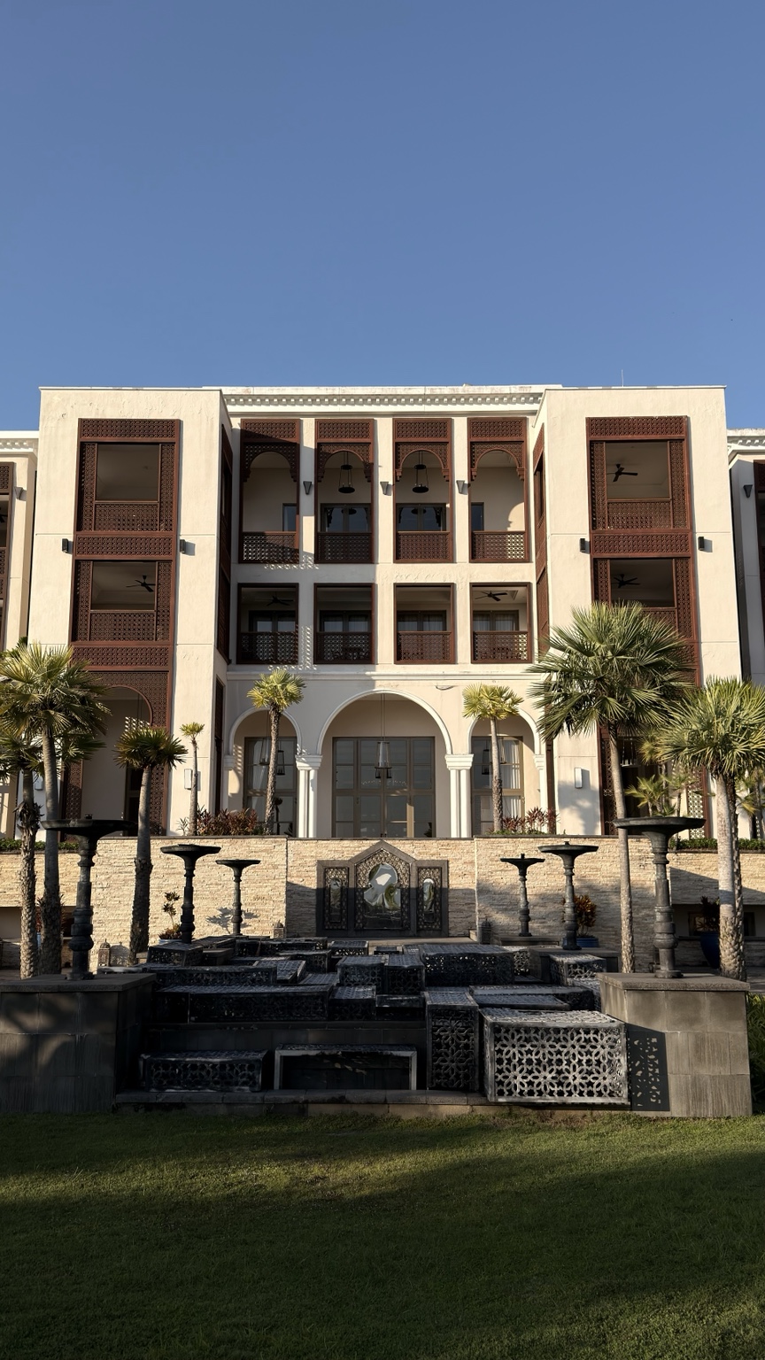 A resort facade with decorative screens, arches and a garden fountain